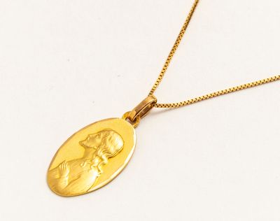 a close up of a gold necklace with a picture of a woman on it