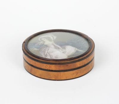 une boîte ovale en bois sur laquelle figure l'image d'une femme en robe blanche