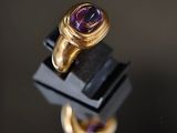 Gros plan sur une bague en or ornée d'une pierre violette.