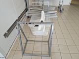 une poubelle blanche posée par terre à côté d'un présentoir métallique