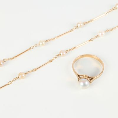 two gold rings and a pearl necklace on a white surface