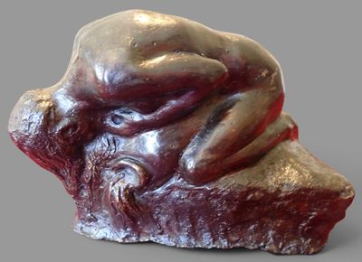 a sculpture of a man laying on top of a rock