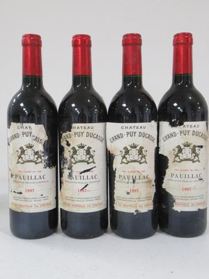 four bottles of wine are lined up in a row on a white surface