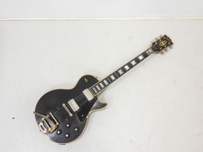 une image représentant une guitare électrique noire posée sur une surface blanche