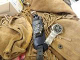 two watches sitting on top of a pile of clothing
