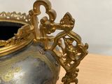 a silver and gold vase sitting on a wooden table