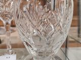a glass vase on a glass table with wine glasses on it