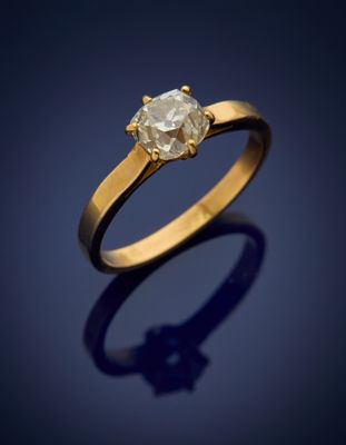 a gold ring with a white diamond on a dark background