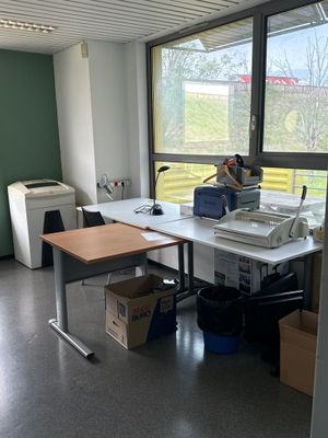 un bureau sur lequel se trouve une imprimante, dans une pièce dotée d'une grande fenêtre