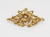 a close up of a gold brooch with a diamond in the center