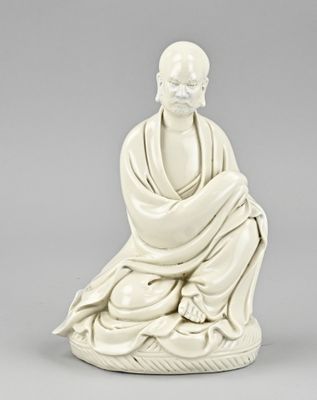 a white figurine of a man sitting in a meditation position