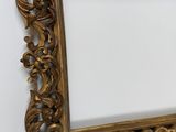 an antique gold frame hanging on a wall with a white background