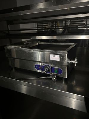 un plan de travail en acier inoxydable surmonté d'un four, dans une cuisine professionnelle