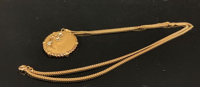 Chaîne et pendentif rond à décor de deux fleurs en or 18 carats 7...