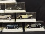 six different model cars are in display cases on a black surface