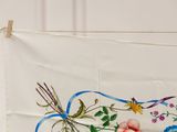 a white towel with a floral design hanging on a clothes line