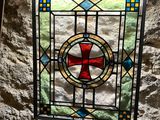 a stained glass window with a red cross on it