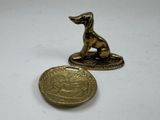 brass dog figurine next to a gold coin on a white surface