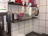 a kitchen with a sink and a bucket of liquid on the shelf