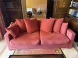a red couch with many pillows on it in a living room