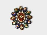 une image représentant une broche multicolore posée sur une surface blanche