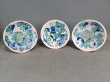 trois assiettes en céramique ornées de motifs, posées sur une table