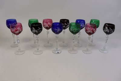 plusieurs verres à vin de couleurs différentes sont alignés sur une surface blanche