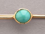 un gros plan d'un lingot d'or orné d'une pierre turquoise