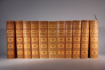 six old books are stacked on top of each other in a row