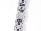 a close up of a diamond and sapphire bracelet on a white surface