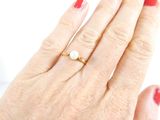 a woman ' s hand with a red manicure and a gold ring