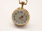 une montre de poche en or avec un cadran blanc sur une surface blanche