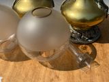 trois vases en verre posés sur une table, avec un vase doré en arrière-plan