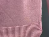 close up of a woman wearing a pink sweater and a black belt