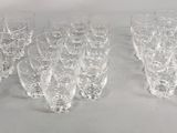six verres à vin transparents sont alignés sur une surface blanche