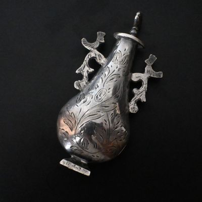 a silver vase with birds on it on a black surface