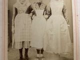 an old photo of three women in dresses standing next to each other