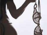 la silhouette d'une femme tenant un soutien-gorge devant une fenêtre