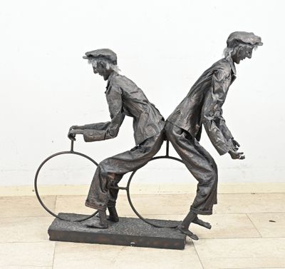 a statue of a man riding a bike and another man riding a bike