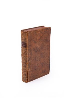 un vieux livre à la couverture brune posé sur une surface blanche