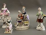 four porcelain figurines of people sitting on top of a table