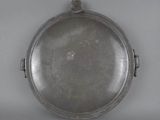an antique silver plate with a handle on a white surface