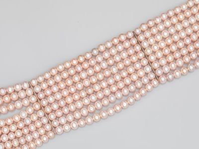 a close up of three rows of pink pearls on a white surface