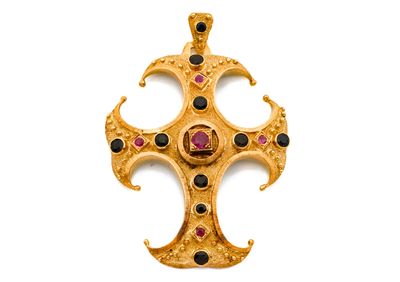 une image représentant une croix en or ornée de pierres noires et rouges