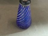 a blue glass bottle with a black top sitting on a table