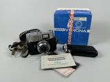 un petit appareil photo et un porte-clés posés à côté d'une boîte
