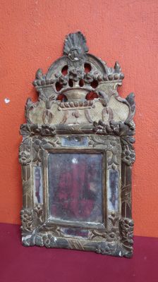 un petit miroir posé sur une table près d'un mur