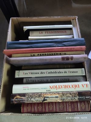 une boîte remplie de livres posée sur une table à côté d'une tasse