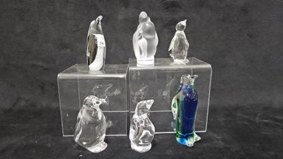 three clear glass figurines of birds on a black background
