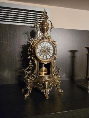 une horloge posée sur une table, à côté de deux bougies